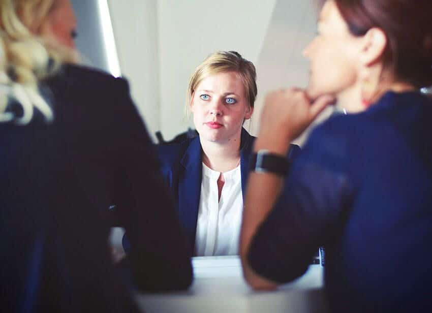 A woman with blond hair staring in the women talking to each other.